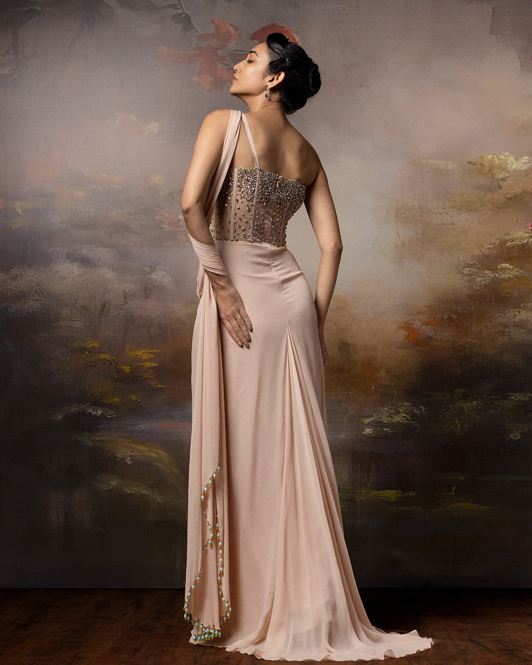 Featuring a beige corset saree gown in gorgette, crepe and net with embroidery on the corset and danglings at the pallu.